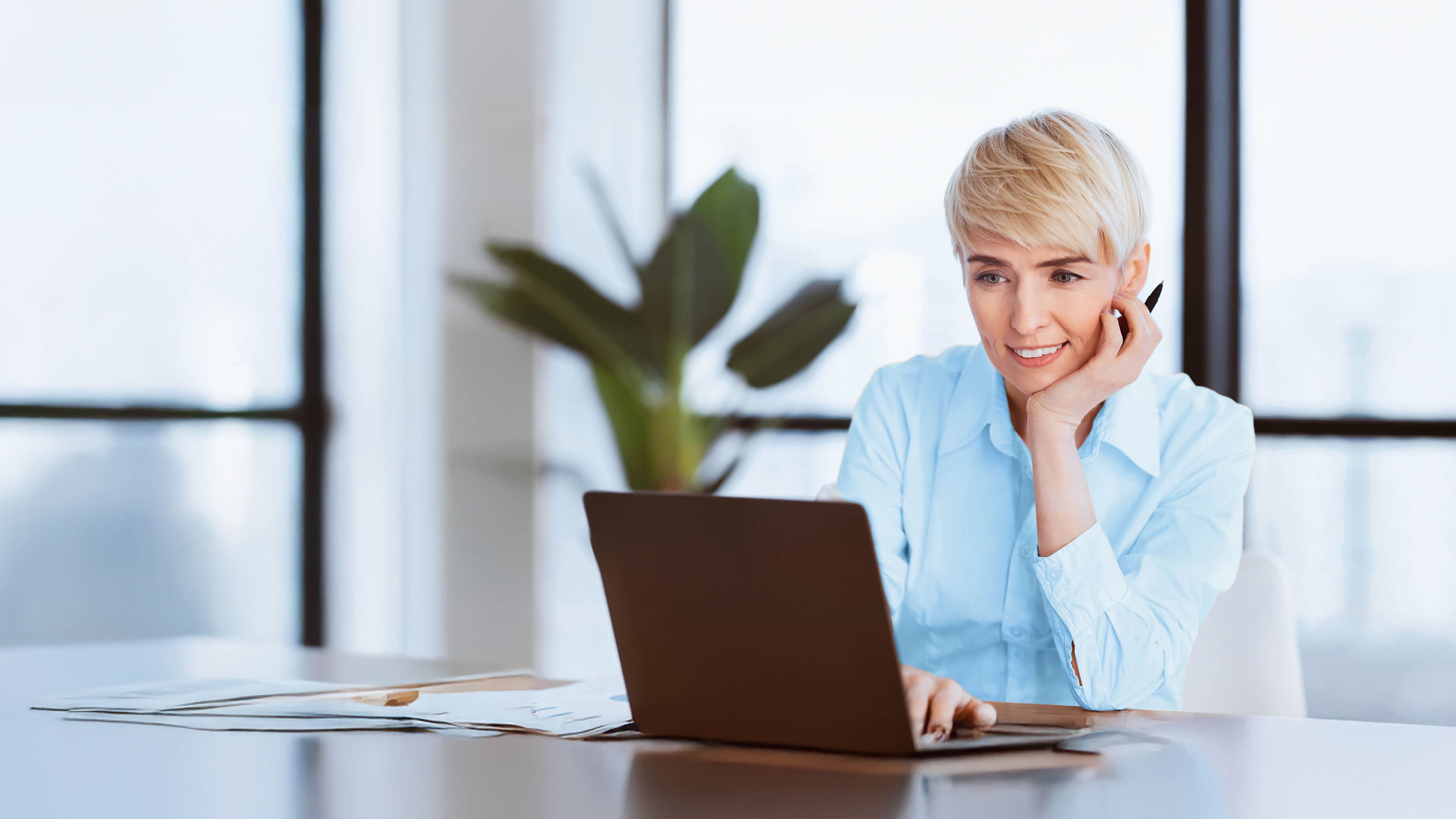 Smiling Mature Business Lady At Laptop Computer Working On A Project Sitting At Workplace In Office. Selective Focus